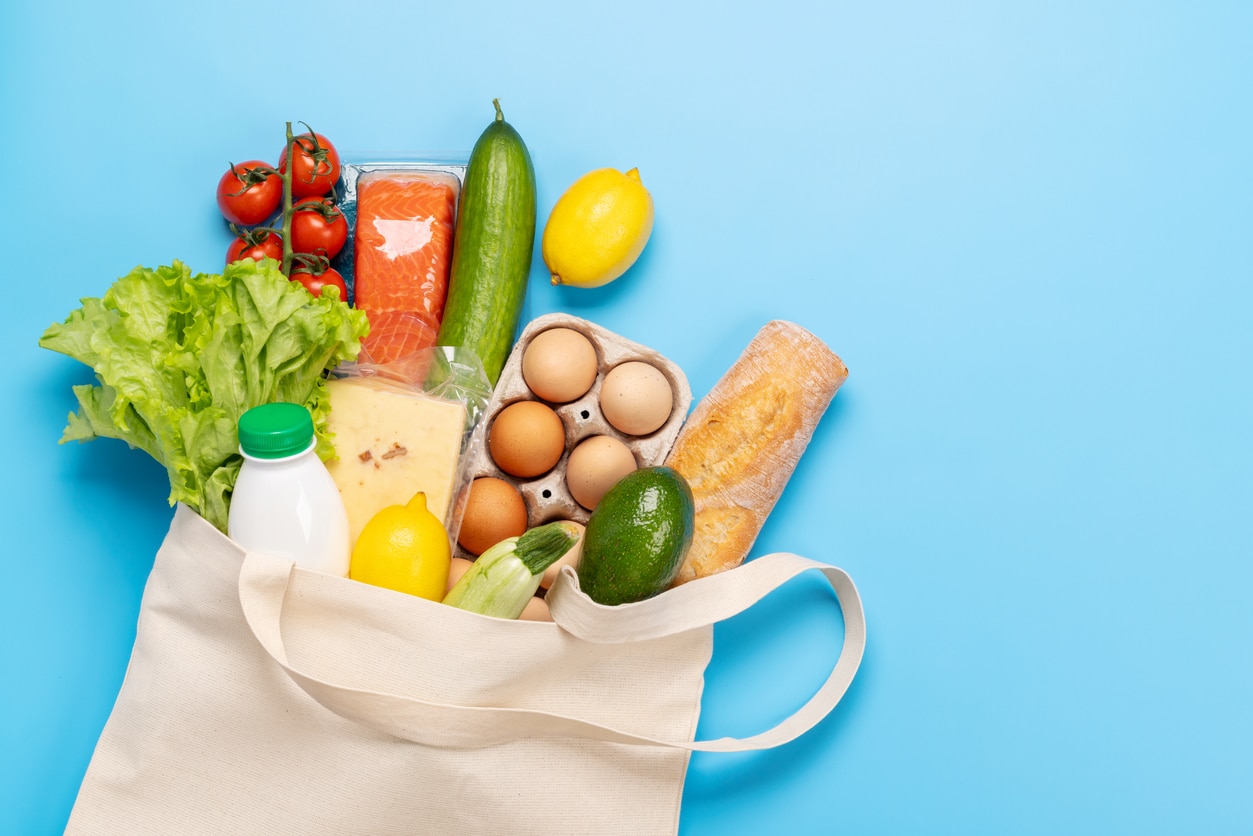 Shopping bag full of healthy food on blue background.